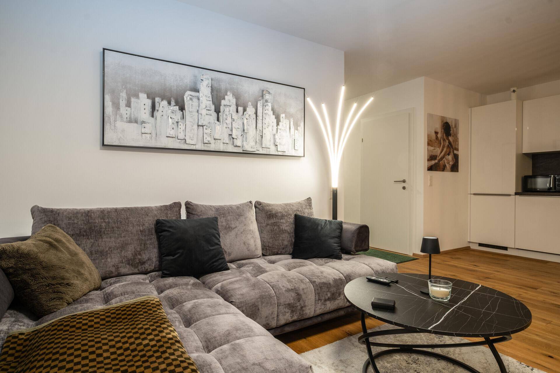 Gemütliches Wohnzimmer mit großer Eckcouch, modernem Kunstwerk und indirekter Beleuchtung.