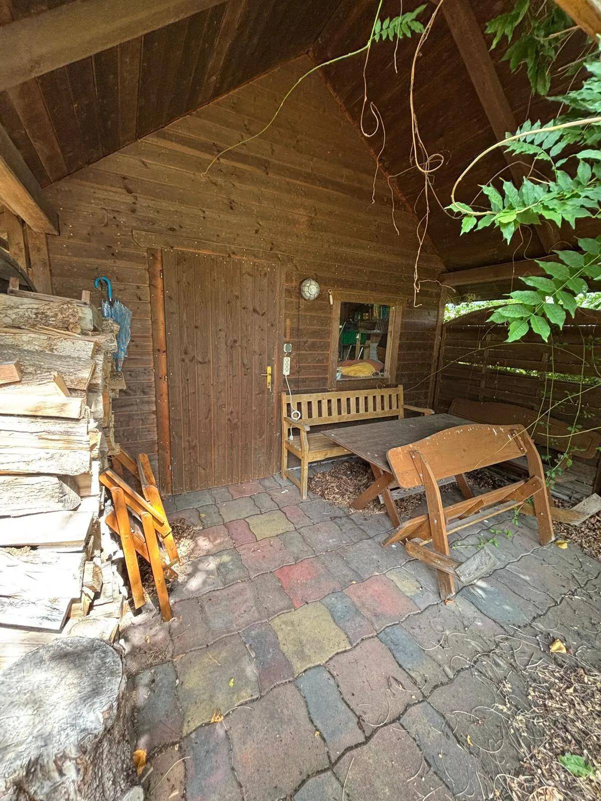 Rustikaler Sitzbereich im Freien neben einem Holzschuppen mit gestapeltem Brennholz.