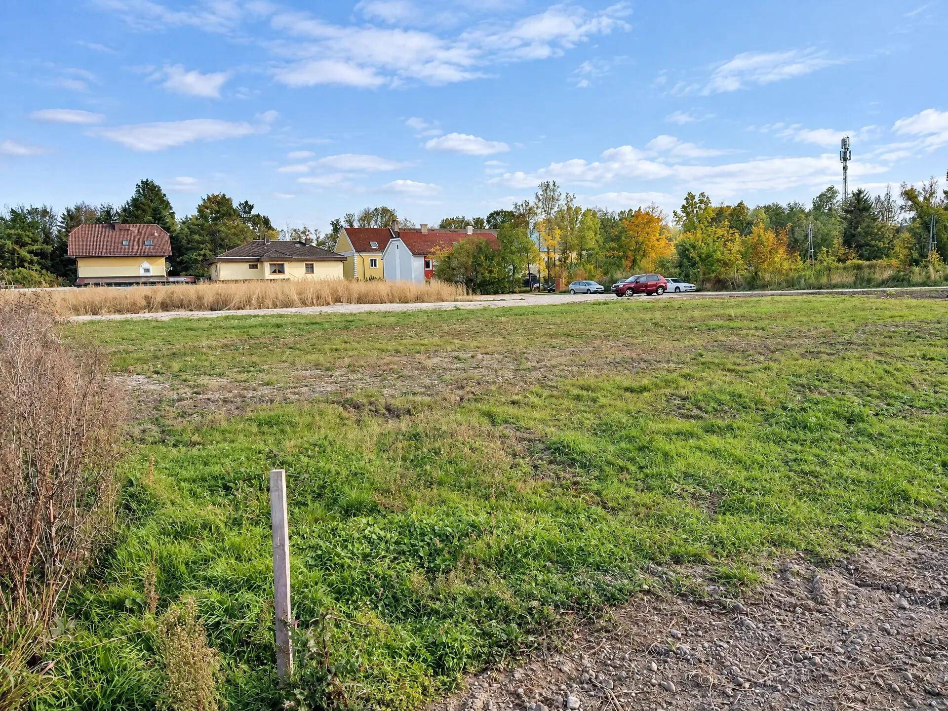 Weitläufiges Grundstück mit Blick auf umliegende Häuser und grüne Landschaft unter blauem Himmel.