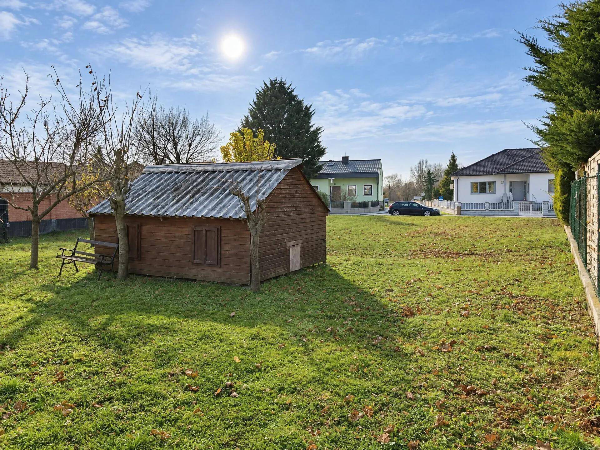Garten mit Rasenfläche, Obstbäumen und einem kleinen Holzschuppen an einem sonnigen Herbsttag.