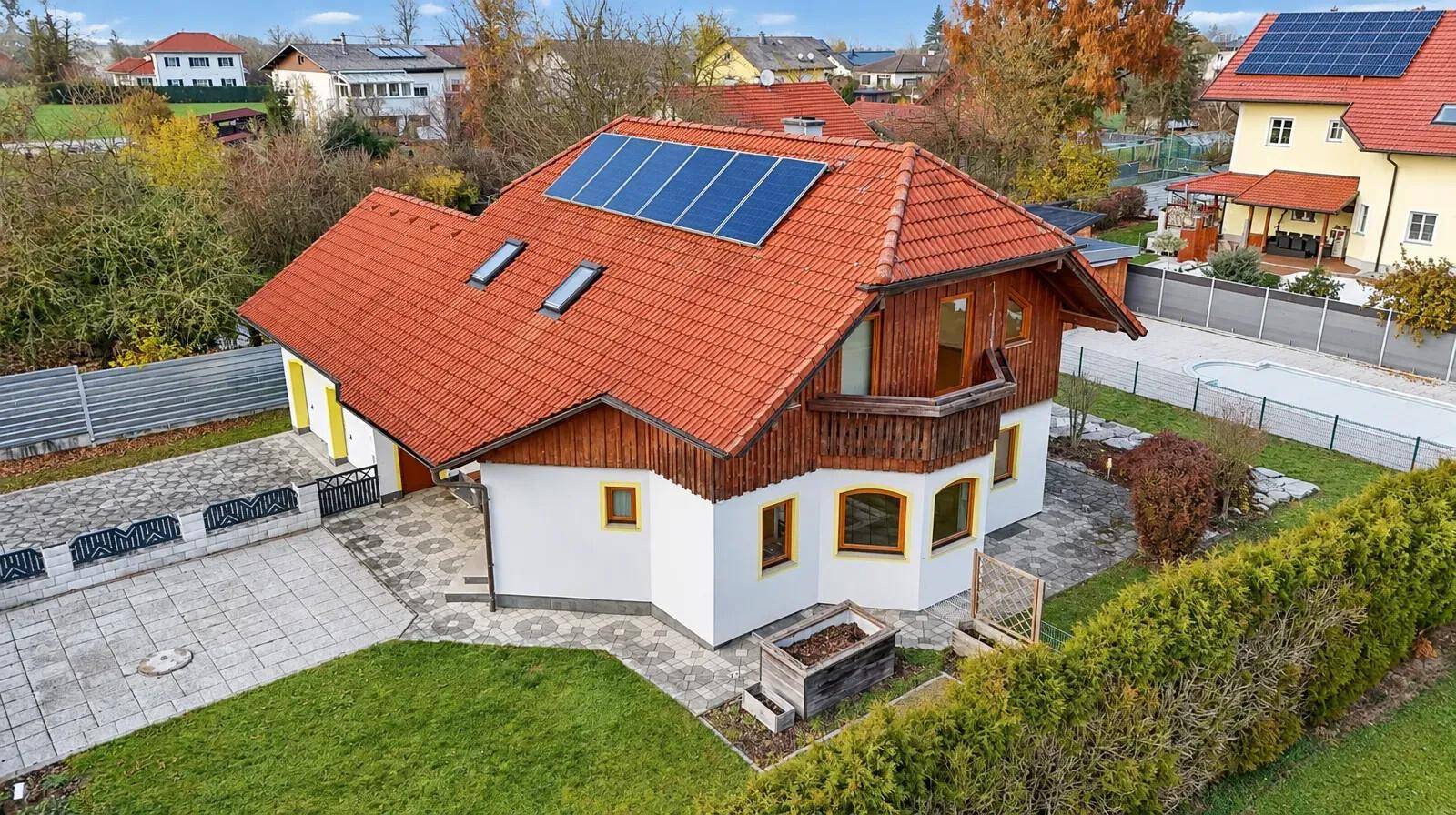 Luftaufnahme des Hauses mit Solaranlage auf dem Dach und Blick auf die Nachbarschaft mit Pool.