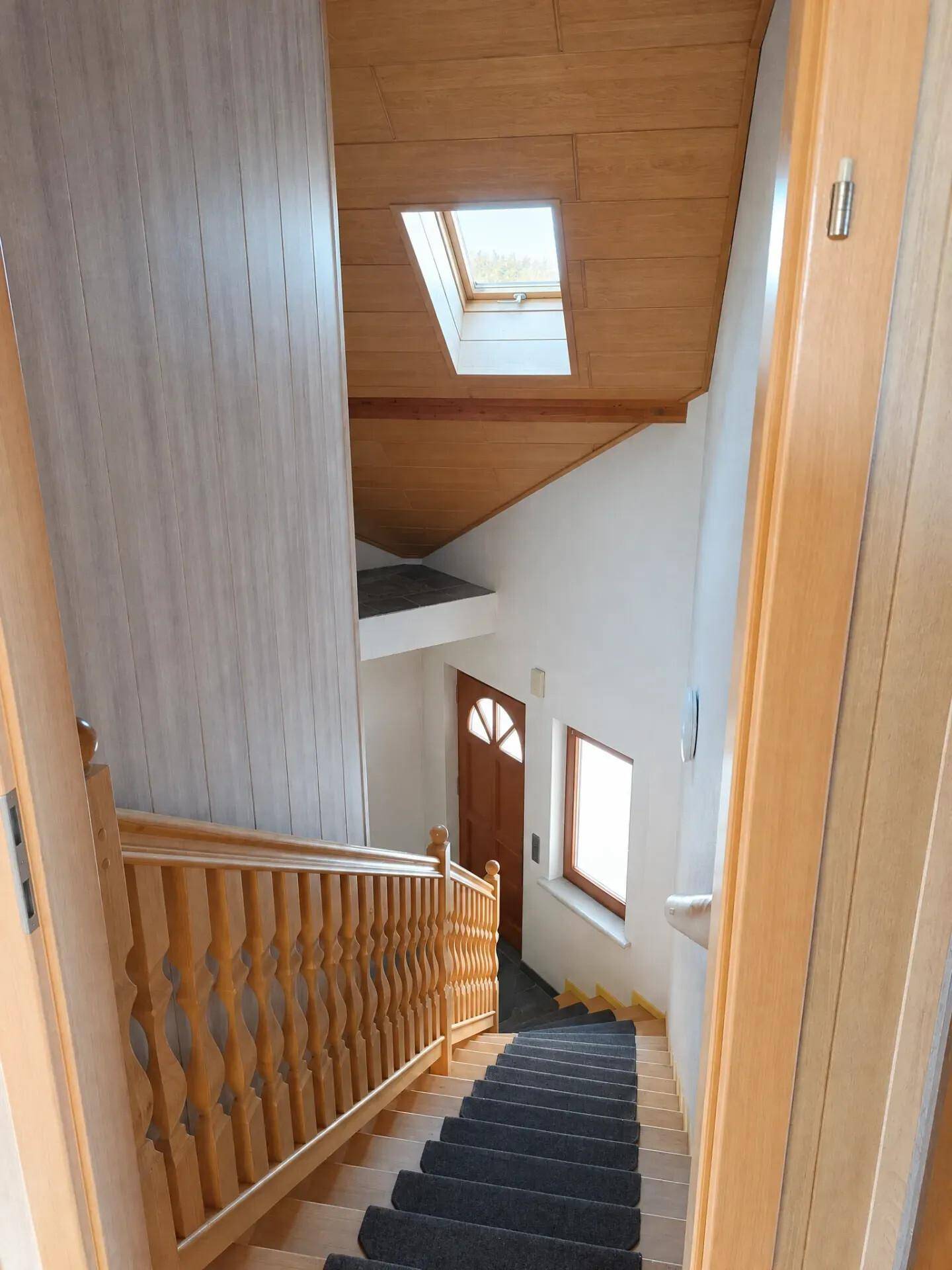 Holztreppe mit Dachfenster, die viel natürliches Licht in den Flur bringt.