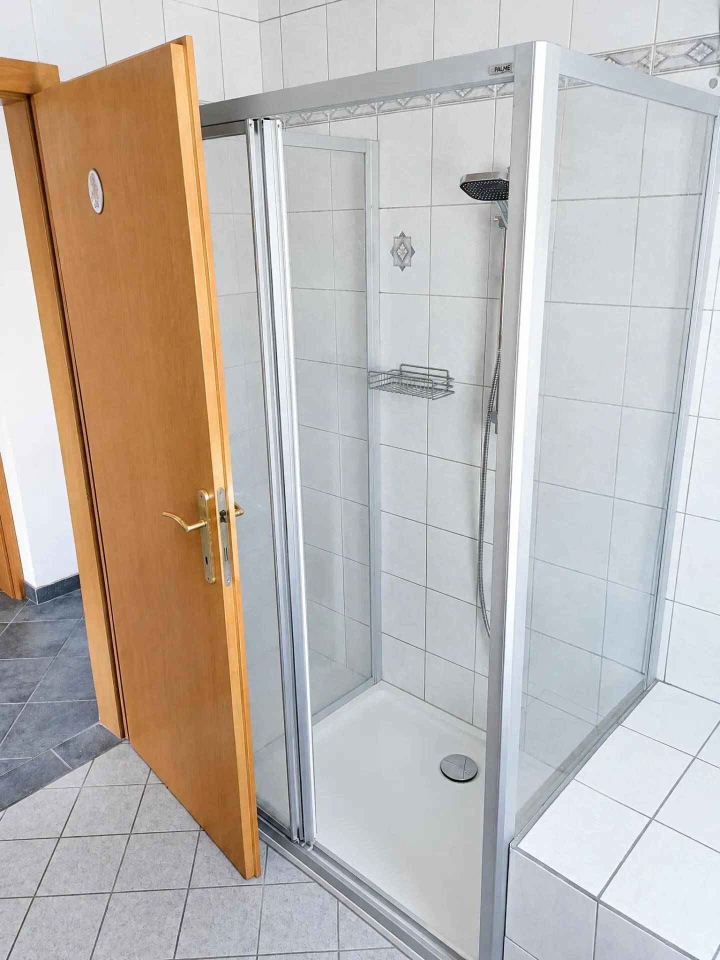 Badezimmer mit Duschkabine und hellen Fliesenboden.