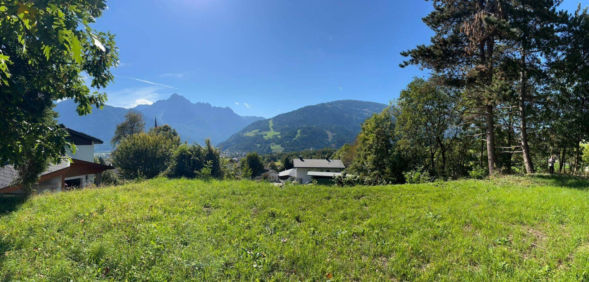 Weitläufiges Grundstück mit Panoramablick auf die umliegende Bergwelt und die sonnige Landschaft.