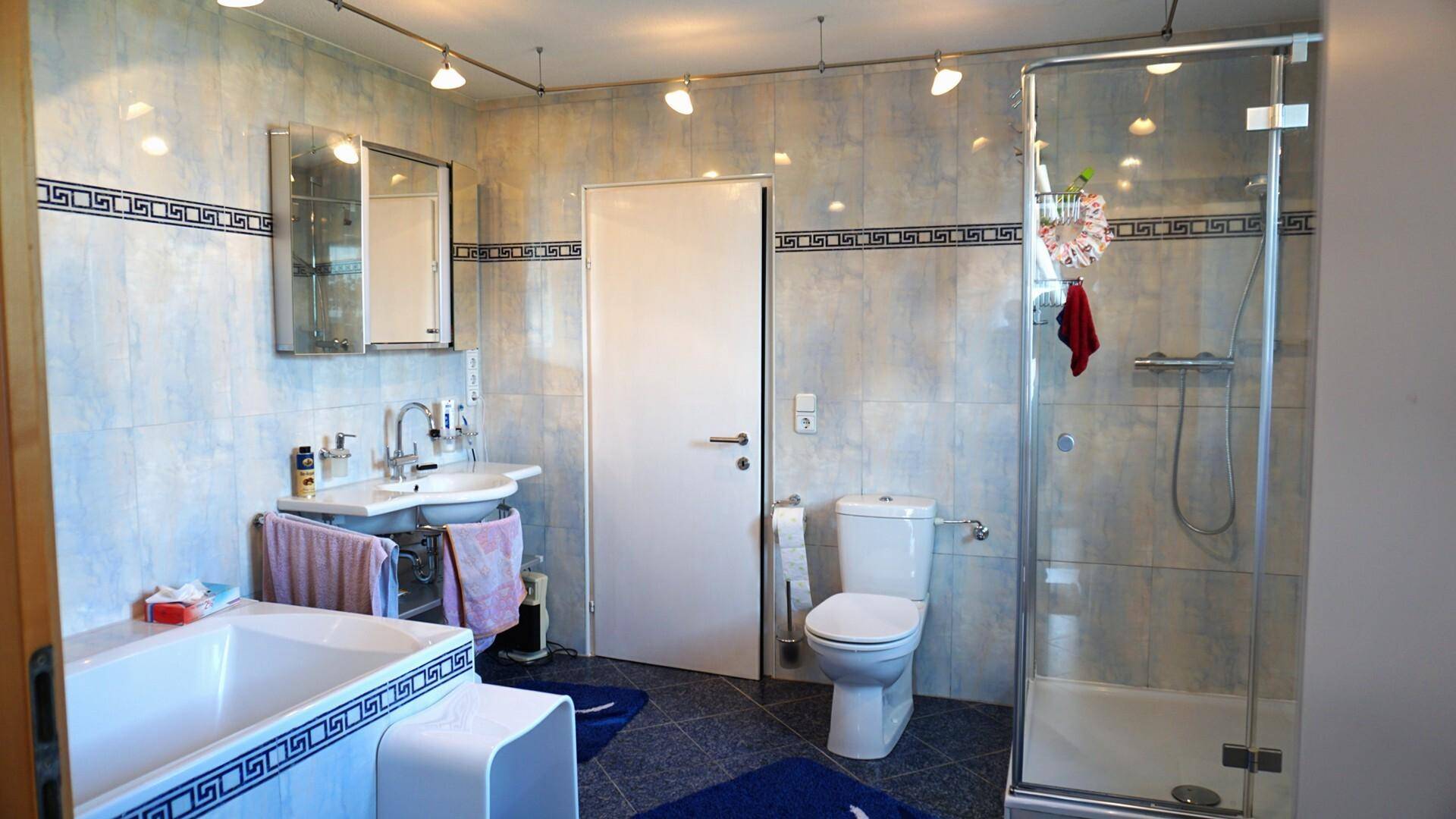 Geräumiges Badezimmer mit Badewanne, Duschkabine, WC und Waschbecken.