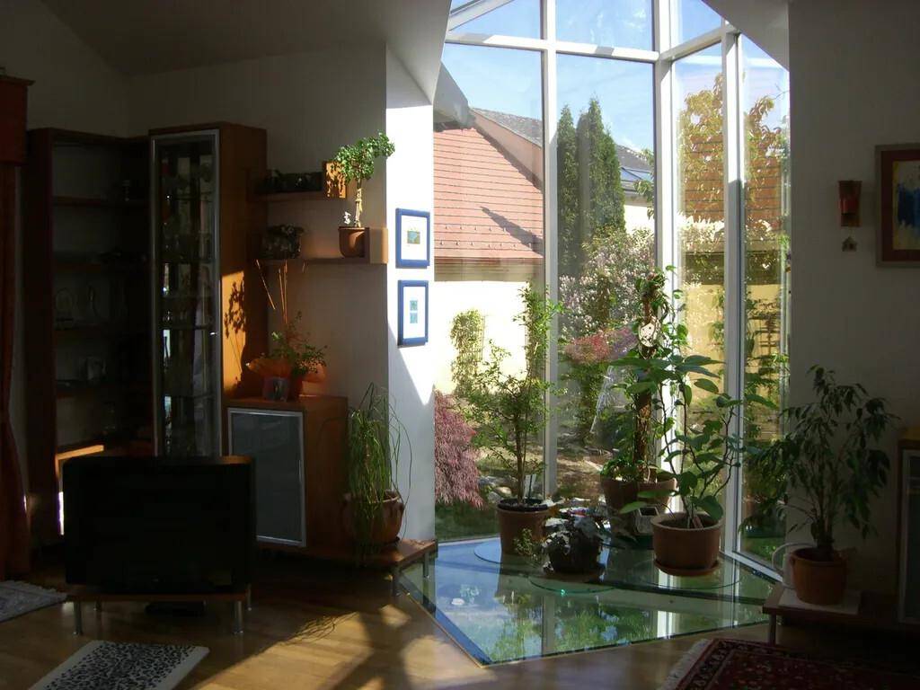 Lichtdurchfluteter Wohnbereich mit großer Glasfront, Holzboden und Blick in den Garten.