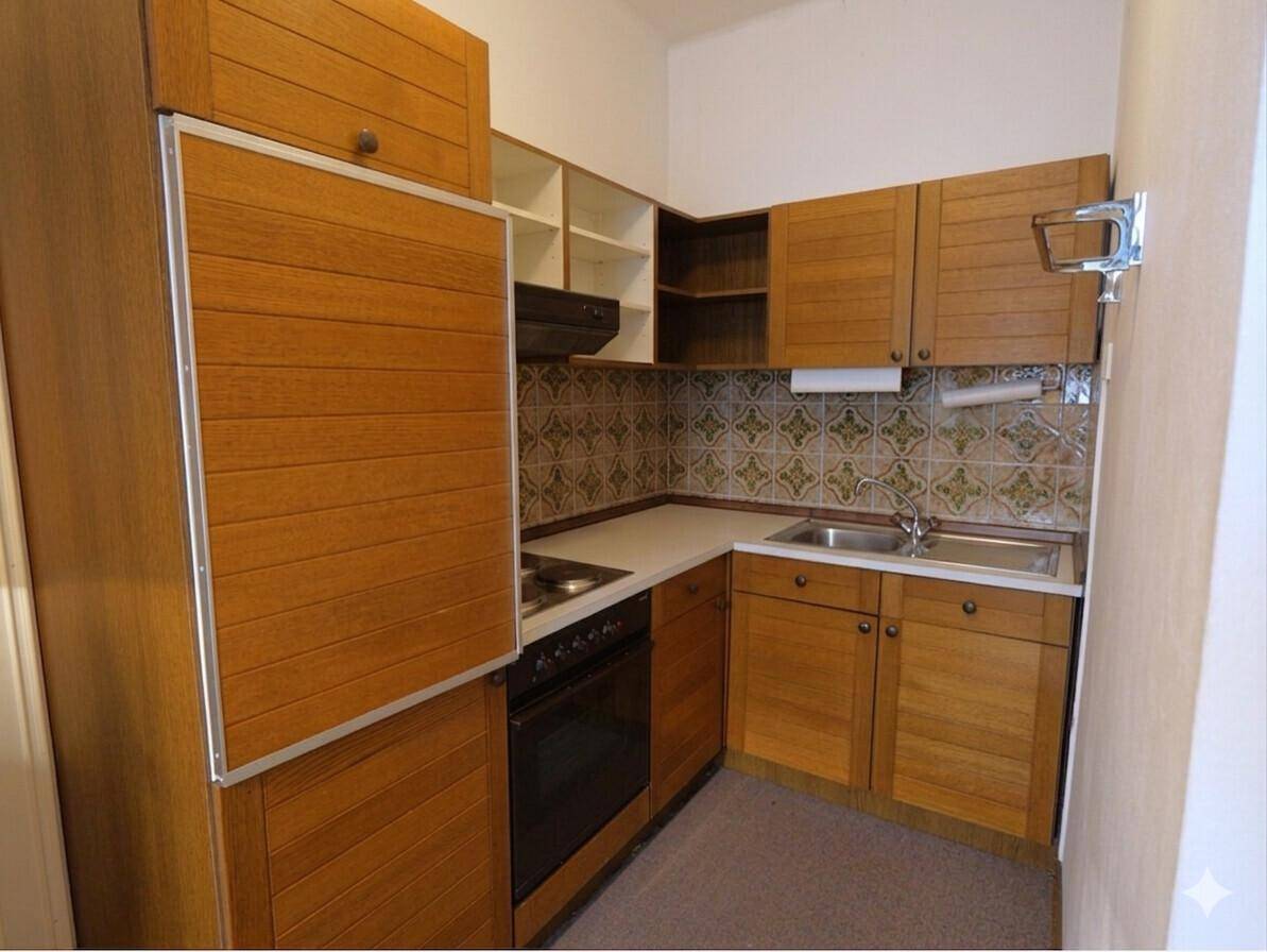 Kleine Küche mit Holzschränken, gemustertem Fliesenspiegel und integrierten Geräten.