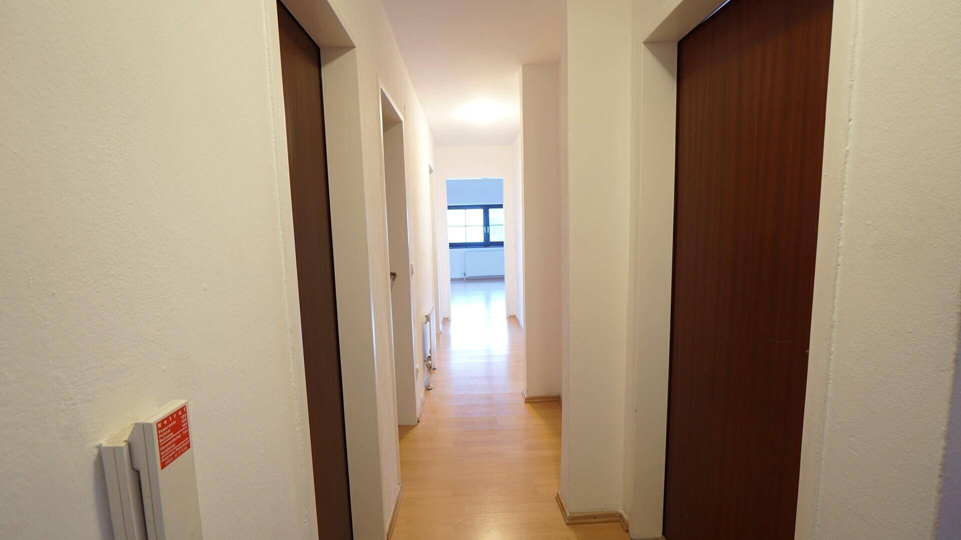 Heller Flur mit Laminatboden und Zugang zu mehreren Zimmern im Dachgeschoss.