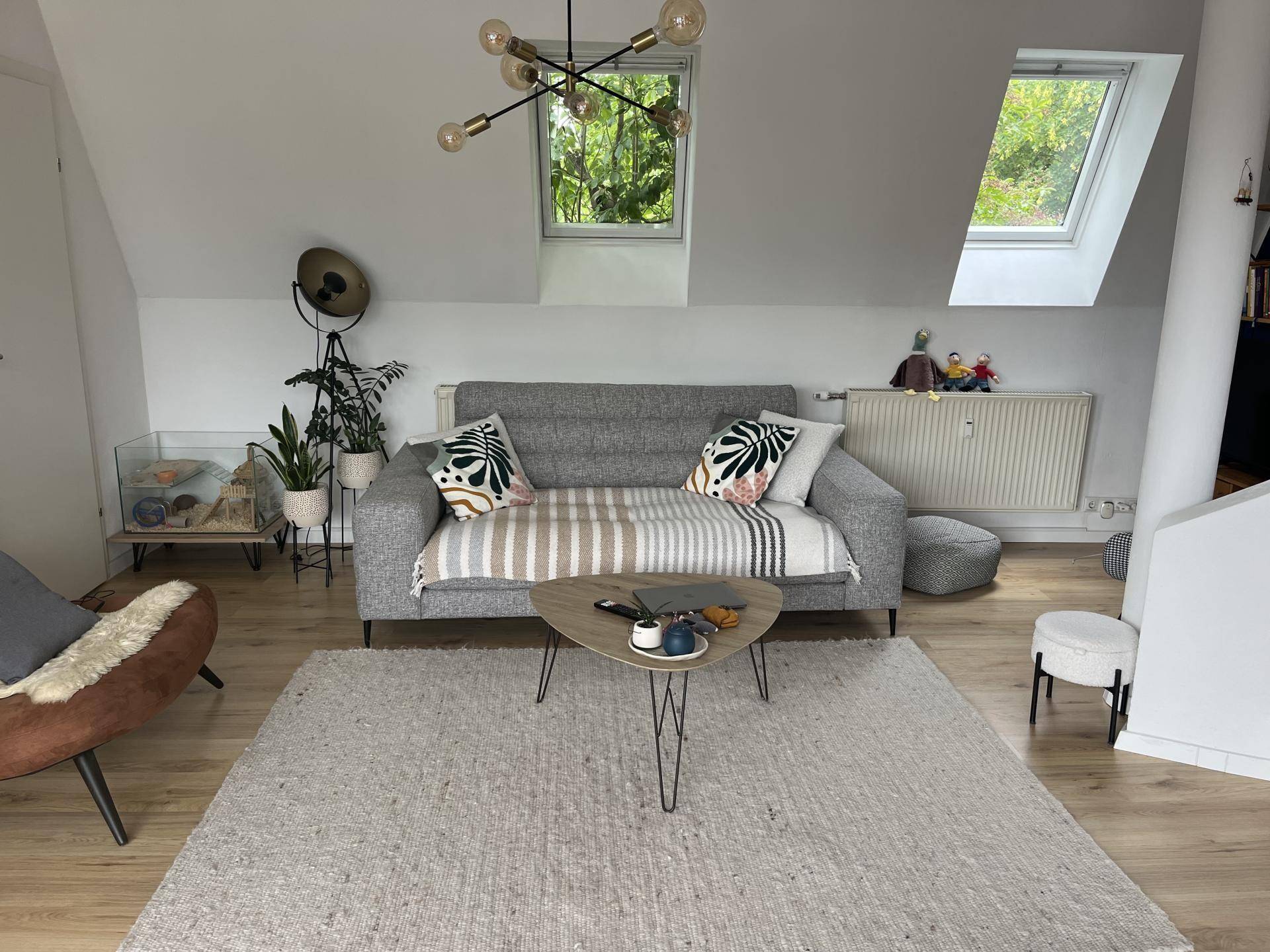 Freundliches Wohnzimmer mit Dachfenstern, hellem Holzboden und Heizkörper.