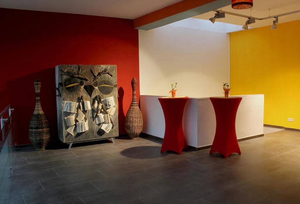 Geräumiger Flur mit roten und gelben Wänden, Kunstmöbeln und Steinfliesenboden.