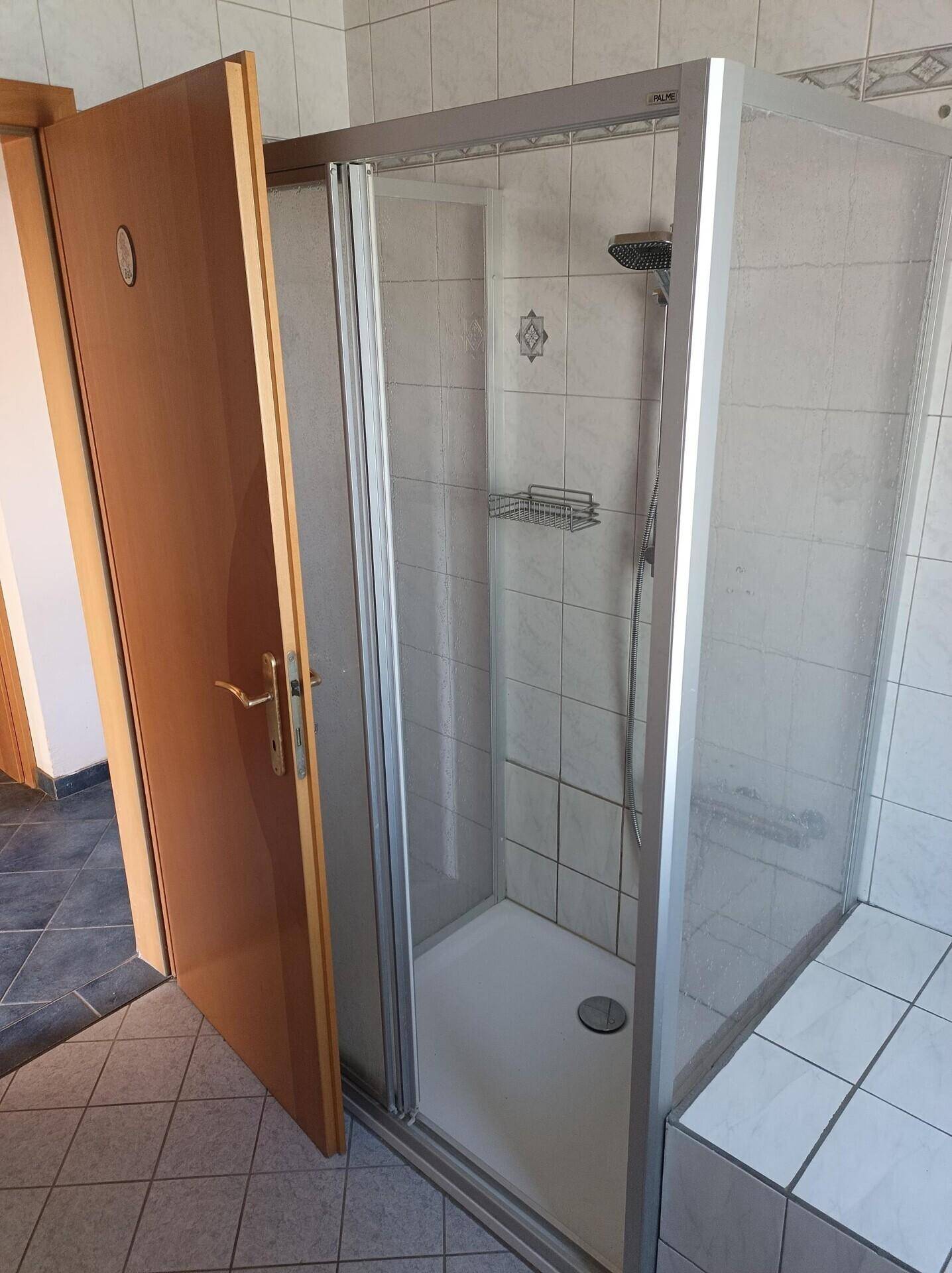 Badezimmer mit Duschkabine und gefliesten Wänden, bereit zur Nutzung.