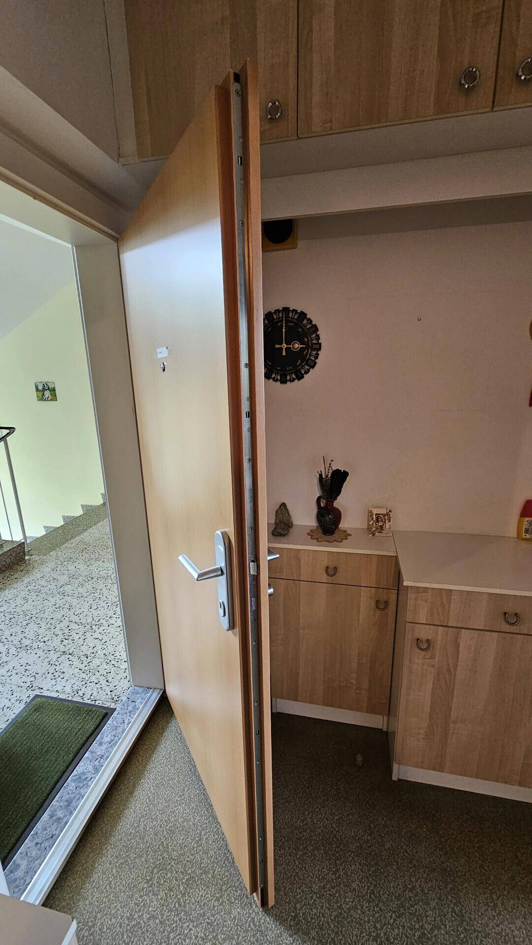Eingangsbereich mit offener Tür zum Treppenhaus und praktischen Holzschränken.
