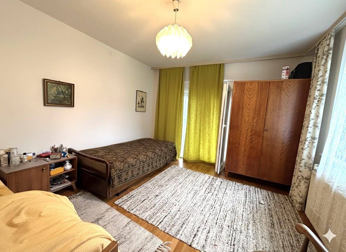 Helles Schlafzimmer mit Einzelbett, Holzschrank und Blick ins Grüne.