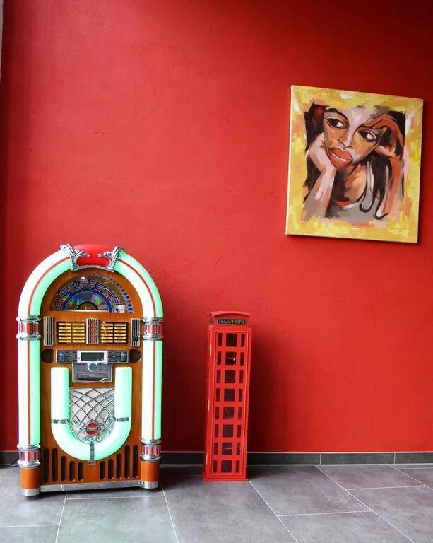Raum mit roter Wand, Jukebox und moderner Kunstdekoration.