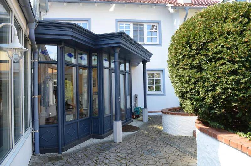 Gepflasterter Innenhof mit einem Wintergarten und einem großen Buchsbaum.