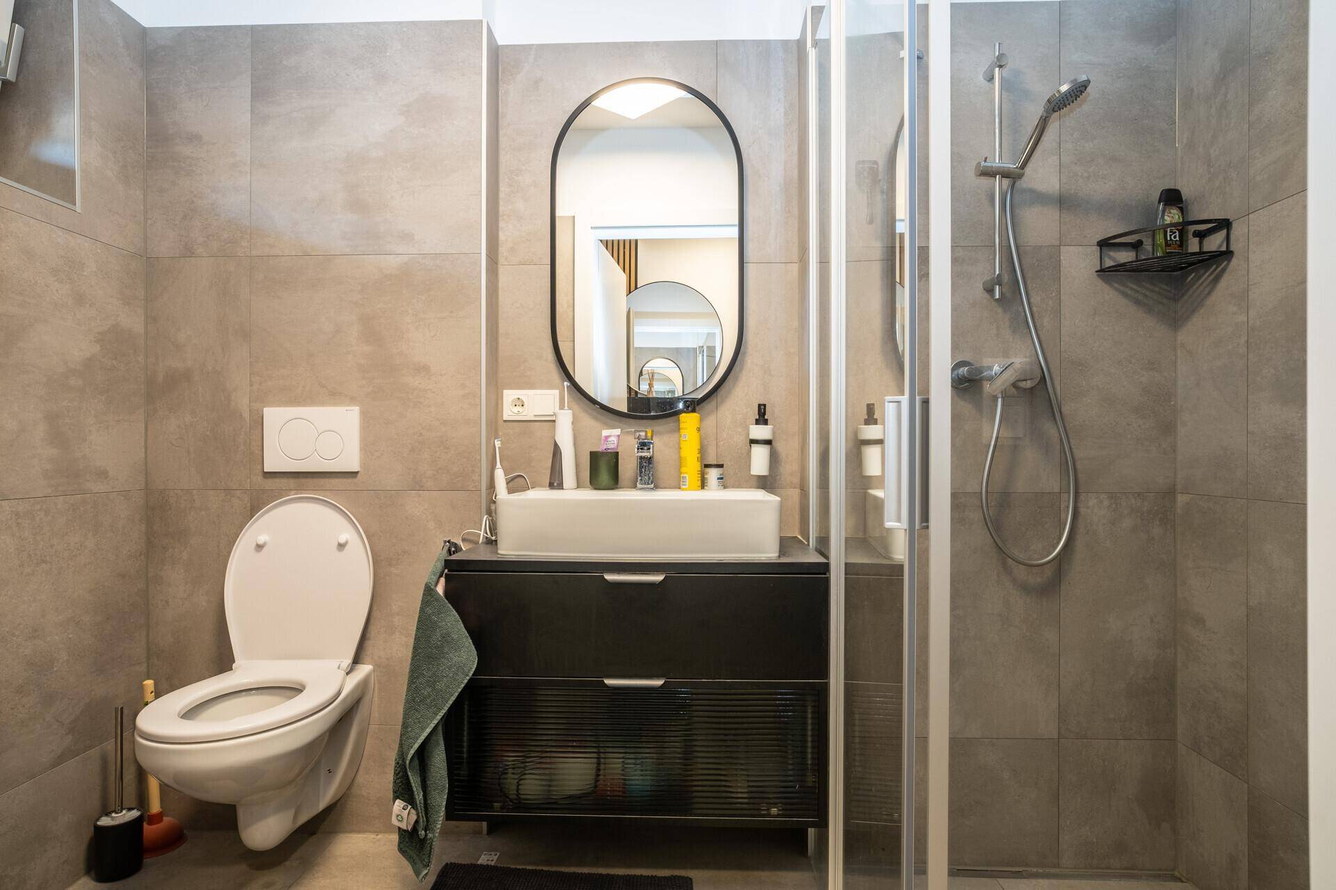 Modernes Badezimmer mit begehbarer Dusche, Wand-WC und eleganten grauen Fliesen.
