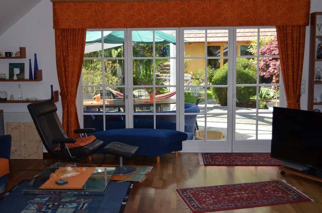 Helles Wohnzimmer mit großen Fenstertüren zum Garten und bequemen Sitzmöbeln.