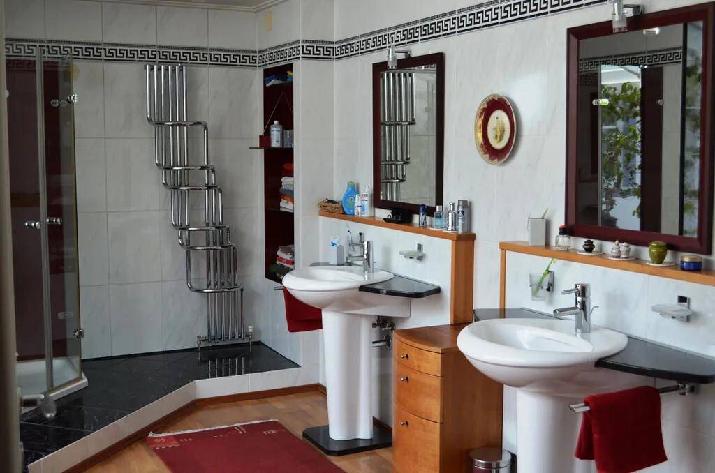 Badezimmer mit zwei Waschbecken, Duschkabine und modernem Handtuchheizkörper.