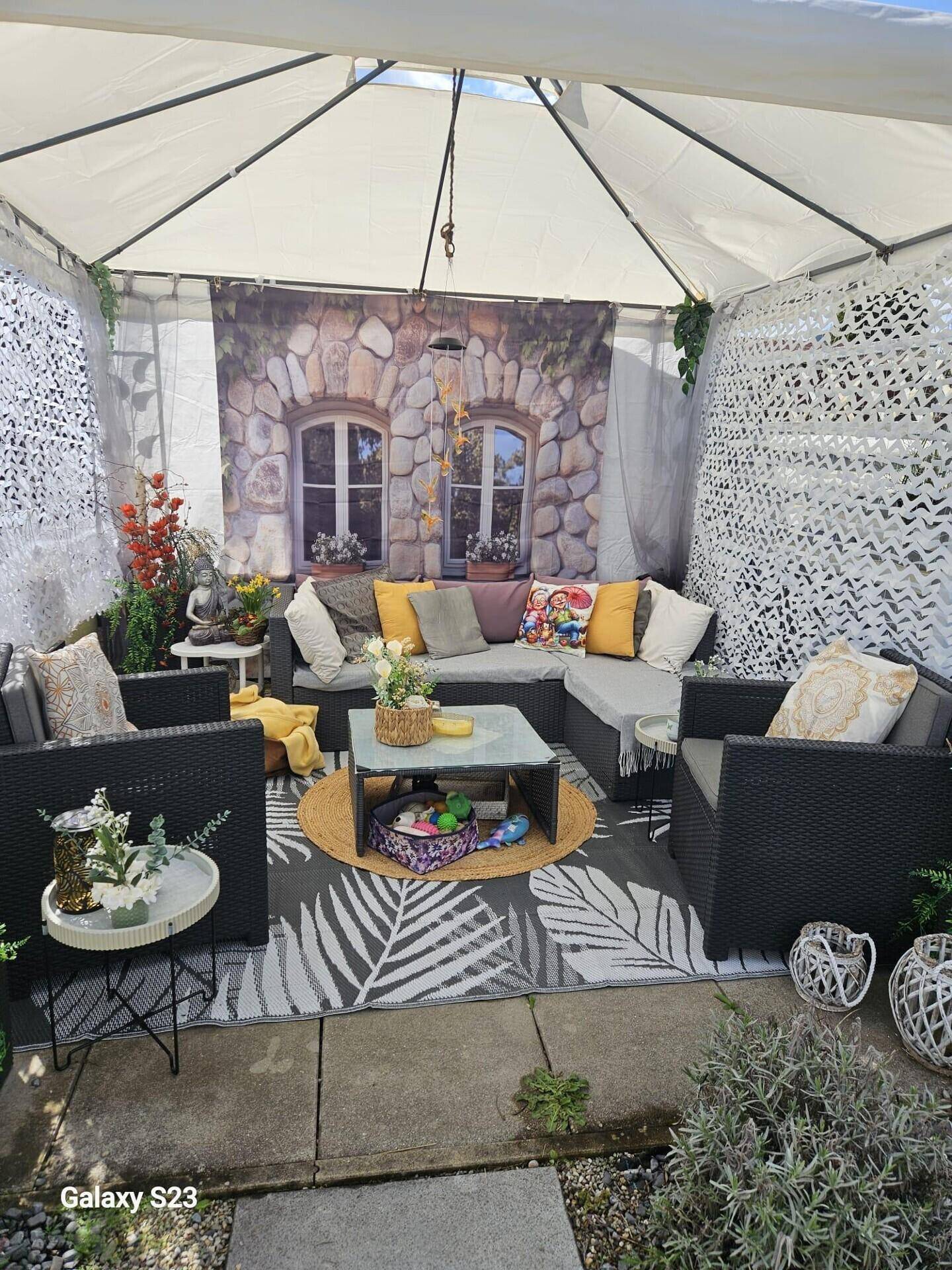 Gemütlicher überdachter Terrassenbereich mit Lounge-Möbeln und dekorativer Wandgestaltung.