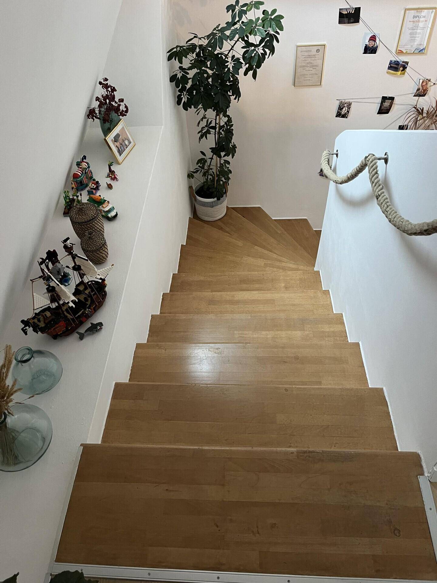 Holztreppe mit Seilgeländer führt zu den oberen Etagen des Hauses.