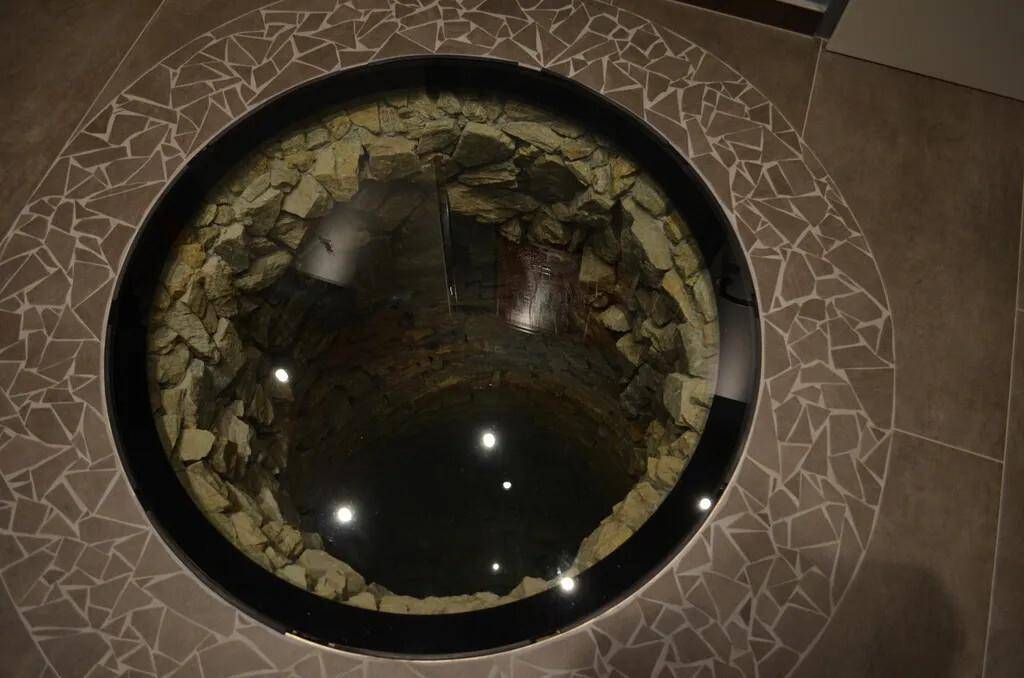 Dekorativer Glasboden über einem alten Brunnen oder Schacht.