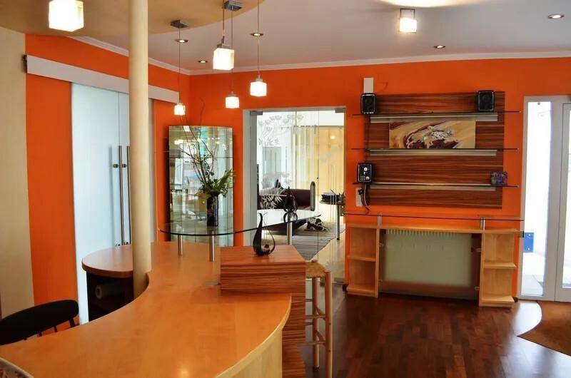Offener Wohnbereich mit Bar, Holzboden und orangefarbenen Wänden.