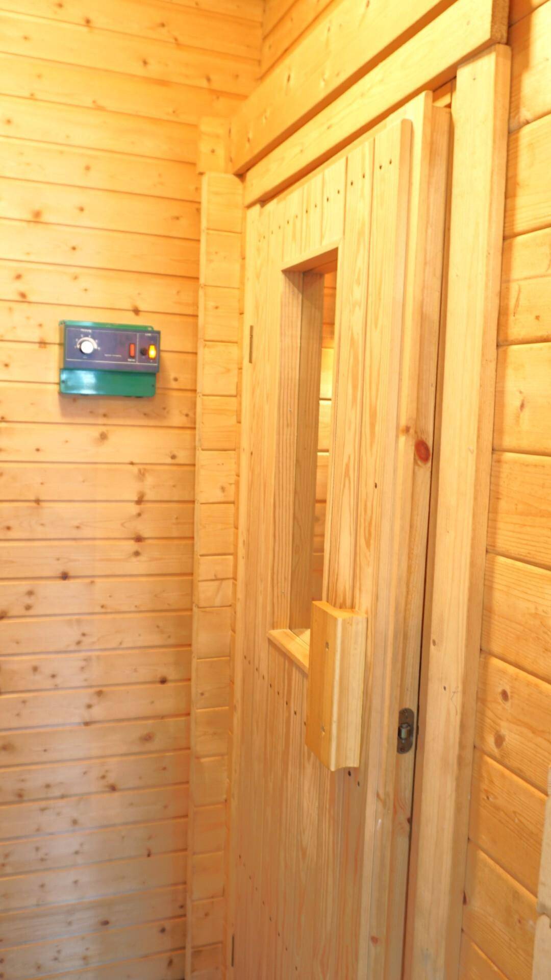 Sauna mit holzverkleideten Wänden und Steuerungselementen für Entspannung.