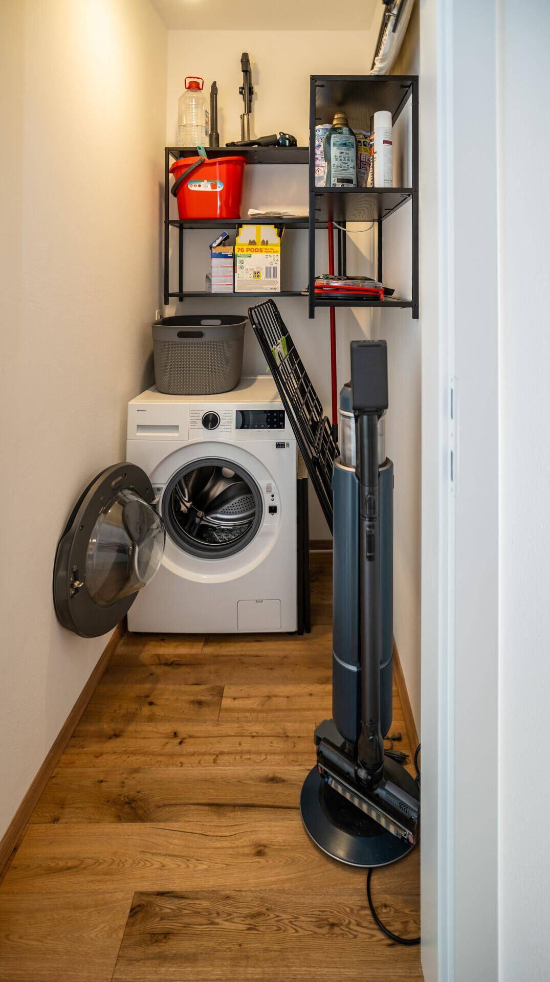Praktischer Hauswirtschaftsraum mit Waschmaschine, Regalen und Stauraum für Reinigungsgeräte.