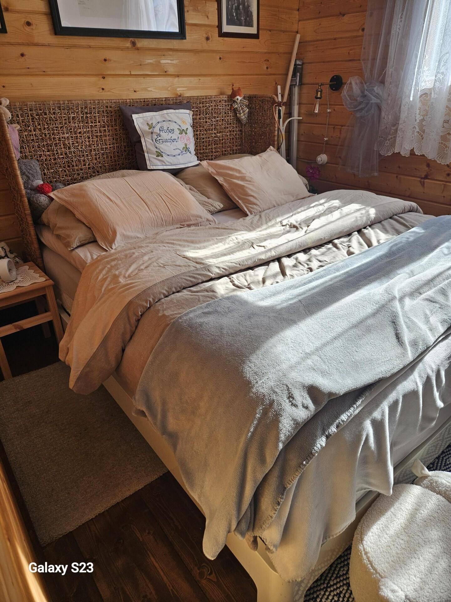 Schlafzimmer mit Holzwänden, Doppelbett und natürlichem Lichteinfall durch das Fenster.