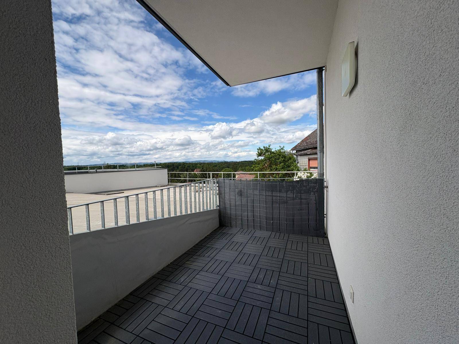 Heller Balkon mit Fliesenboden und Metallgeländer, bietet weite Aussicht auf die Landschaft.