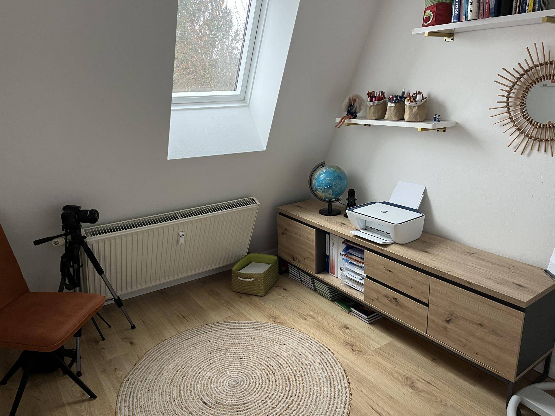 Helles Arbeitszimmer im Dachgeschoss mit Schreibtisch und Dachfenster.