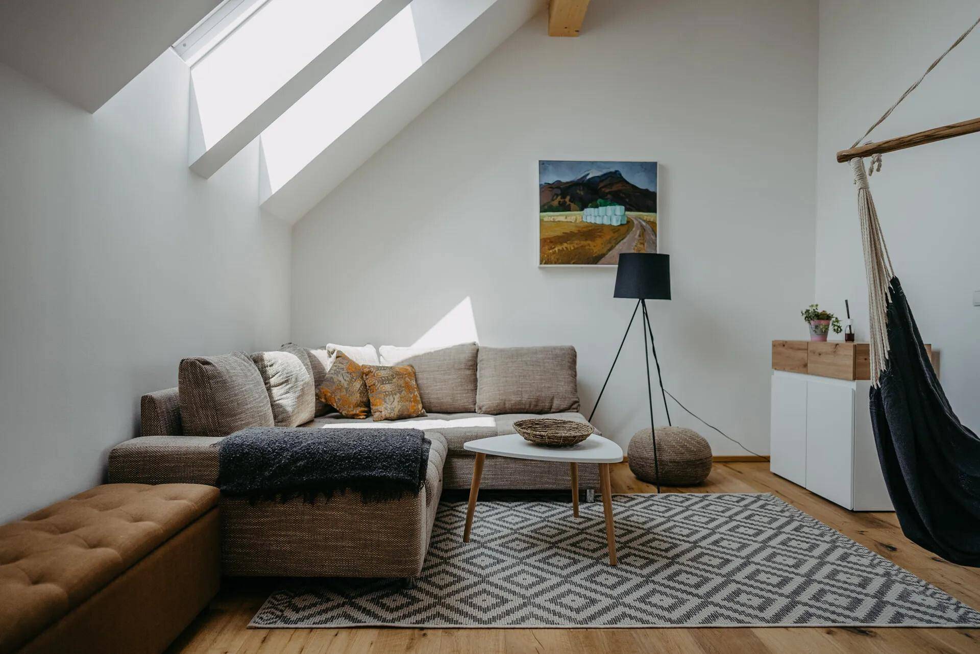 Helles Wohnzimmer mit Dachschrägen, Holzbalken und gemütlicher Sitzecke.