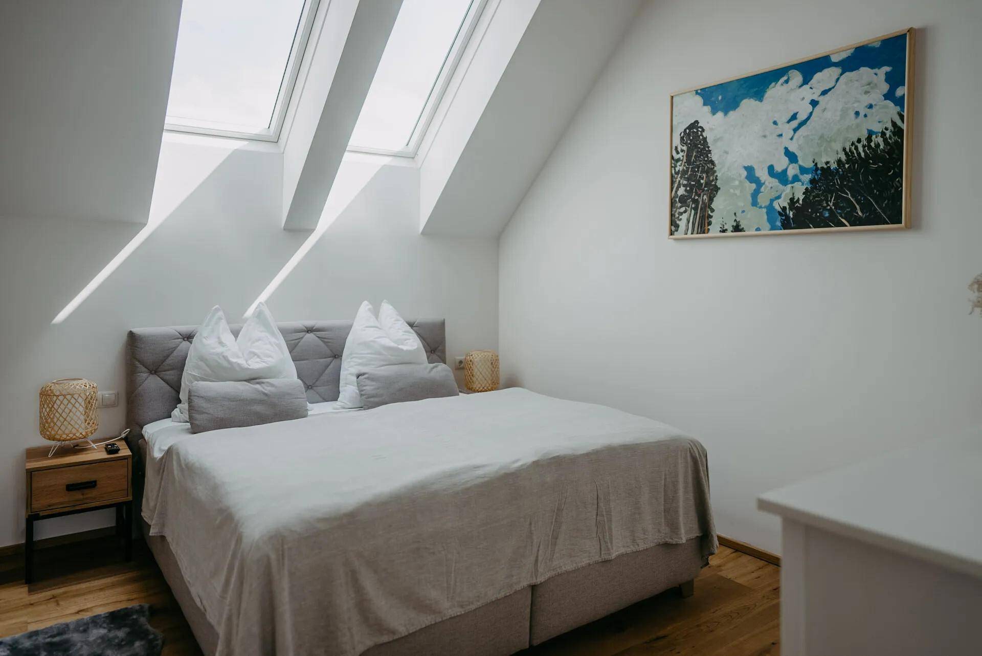 Geräumiges Schlafzimmer mit viel Tageslicht durch Dachfenster und komfortablem Bett.