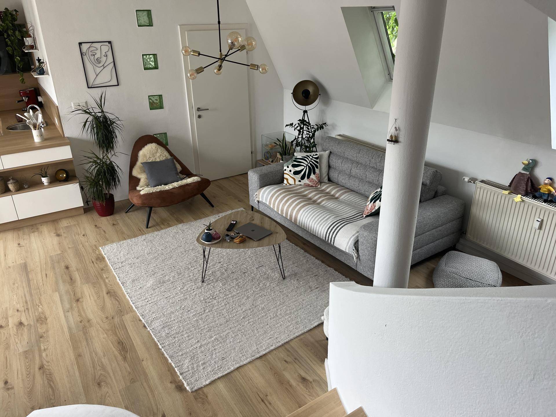 Heller Wohnbereich im Dachgeschoss mit bequemer Couch und Holzboden.