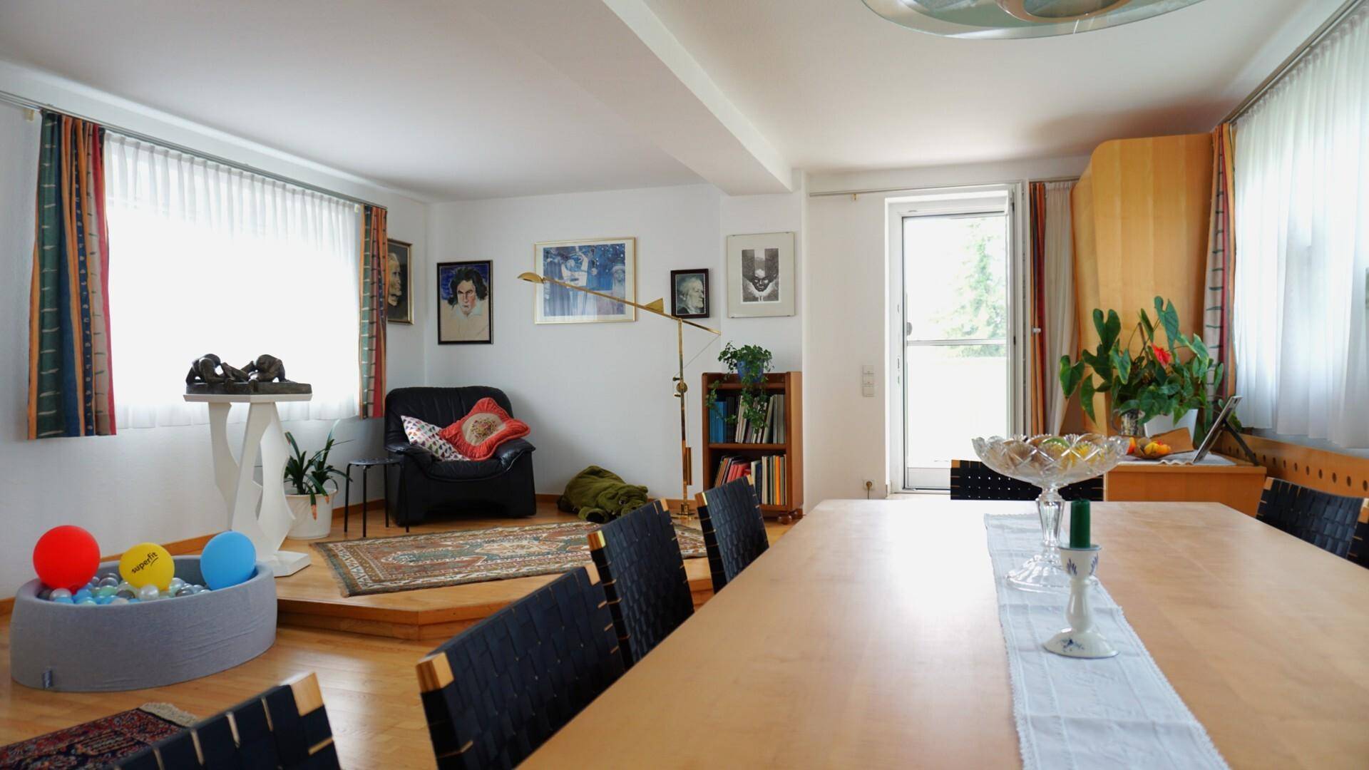 Heller Essbereich mit Holztisch, Teppich und einem kleinen Sitzbereich am Fenster.