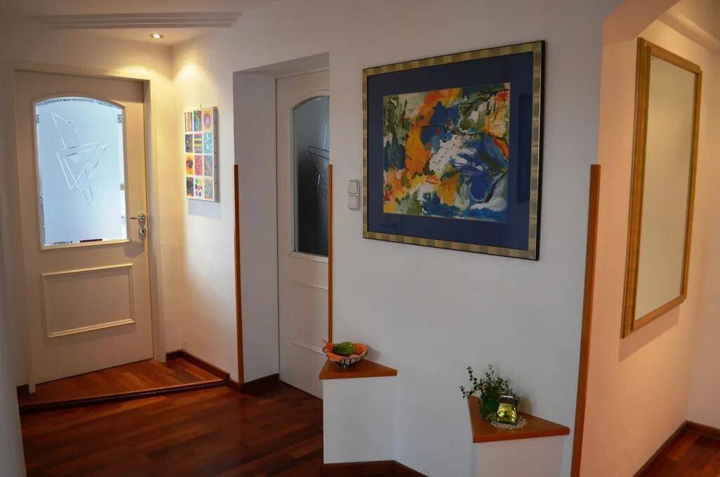 Heller Flur mit Holzboden, Kunstwerken und einer Tür mit Milchglas.