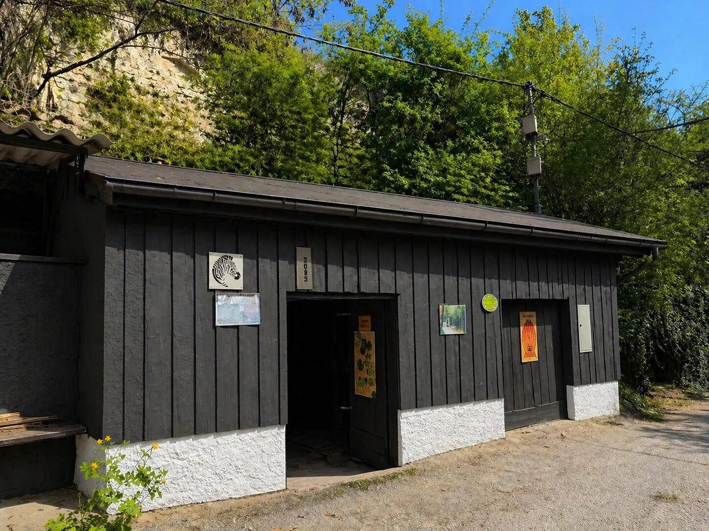 Modernisierte Fassade eines Nebengebäudes mit dunklen Holzpaneelen und einem flachen Dach.