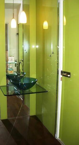 Modernes Badezimmer mit grün gestrichenen Wänden, Glaswaschbecken und Pendelleuchten.