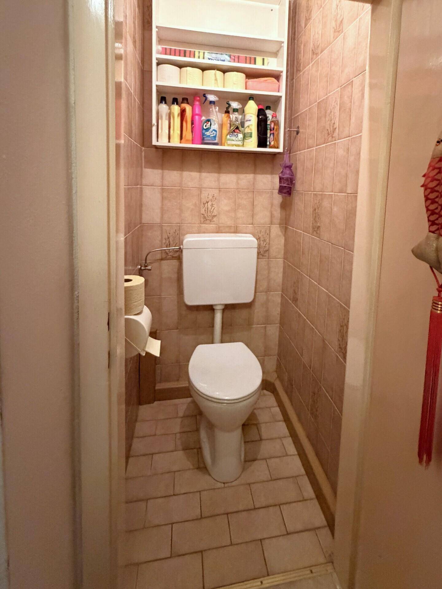 Separate Toilette mit Fliesenboden und Wandfliesen.