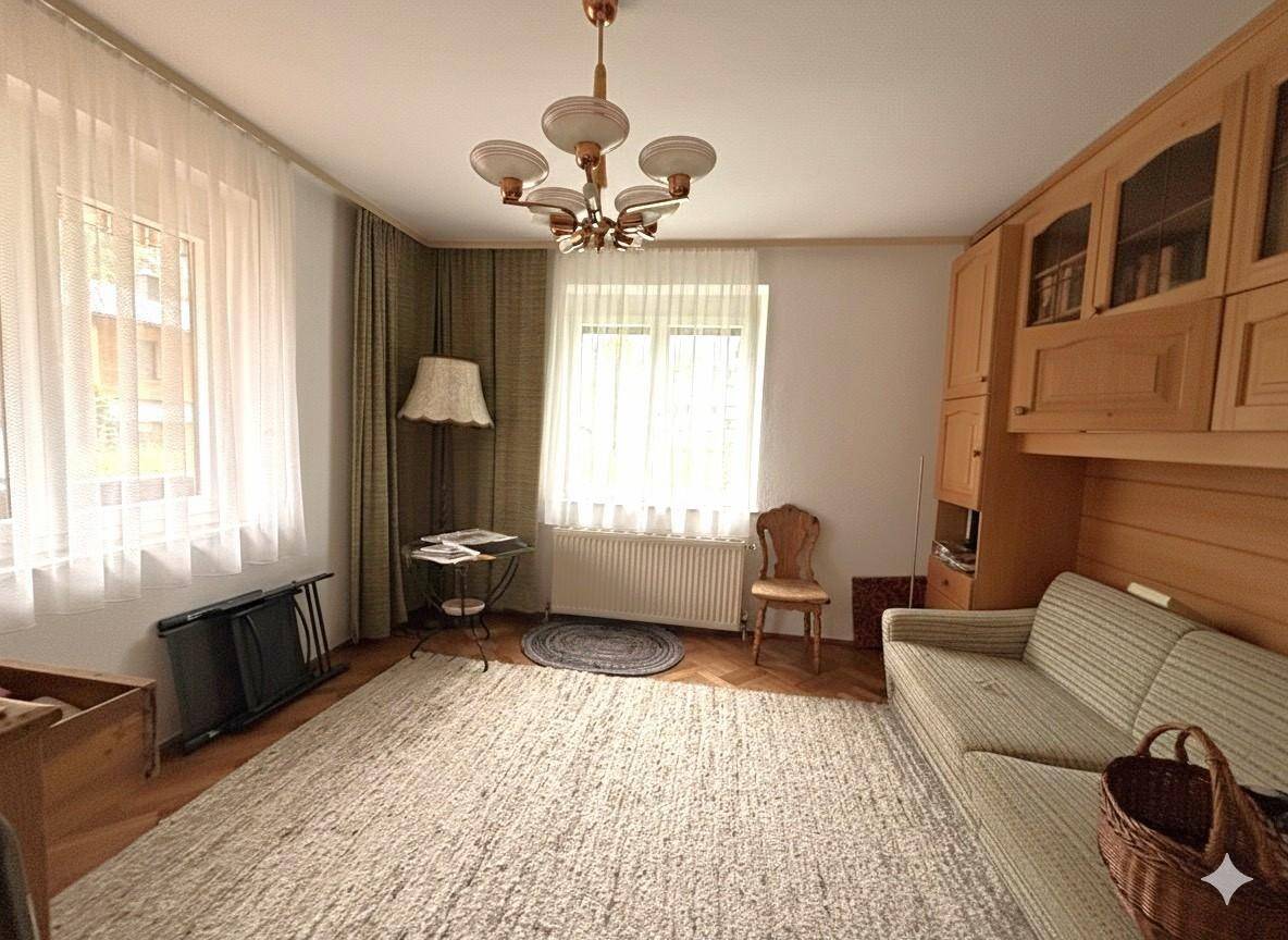 Helles Wohnzimmer mit Parkettboden, bequemer Couch und traditionellen Möbeln.