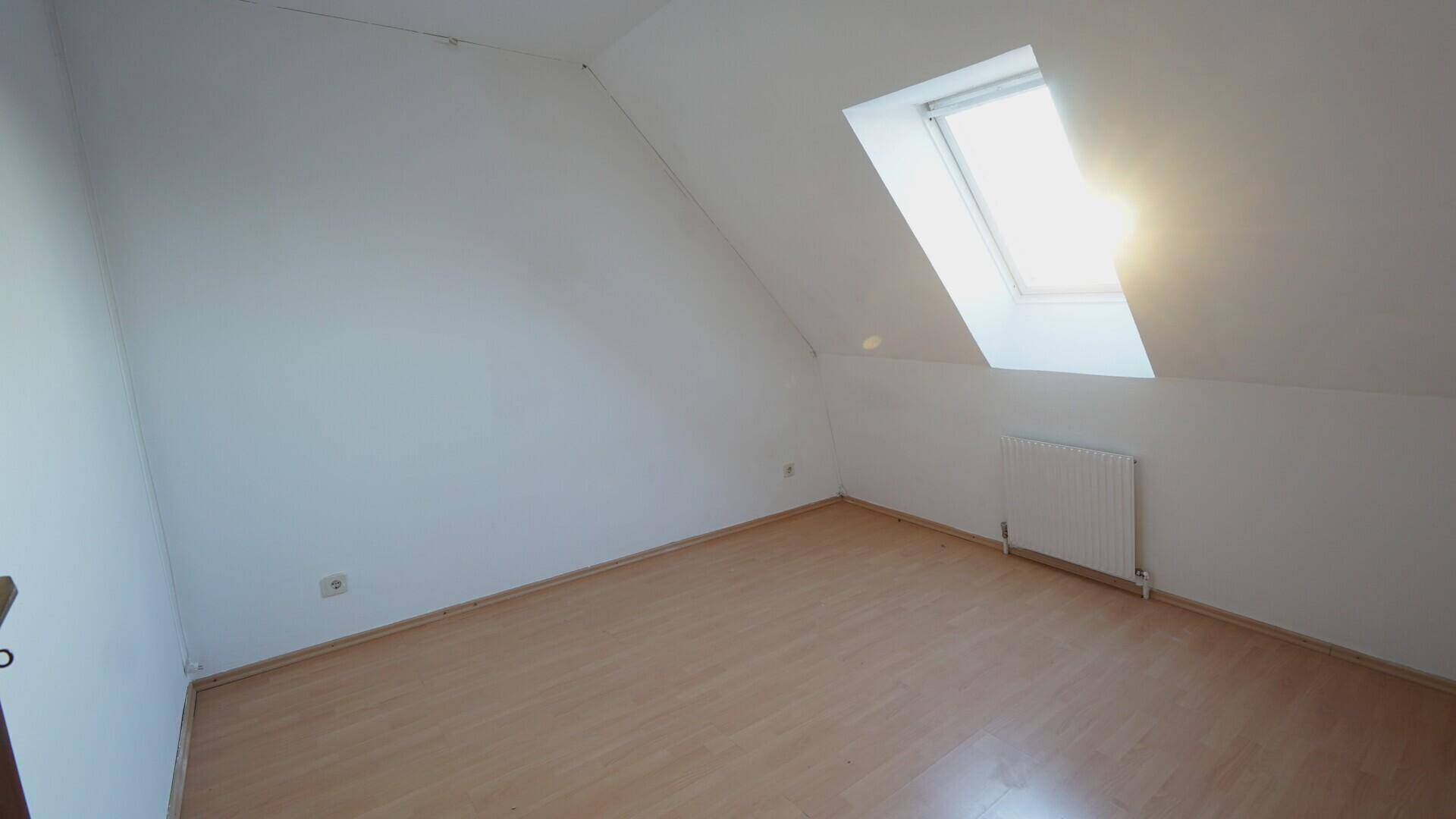 Gemütliches Schlafzimmer im Dachgeschoss mit Laminatboden und hellem Dachfenster.