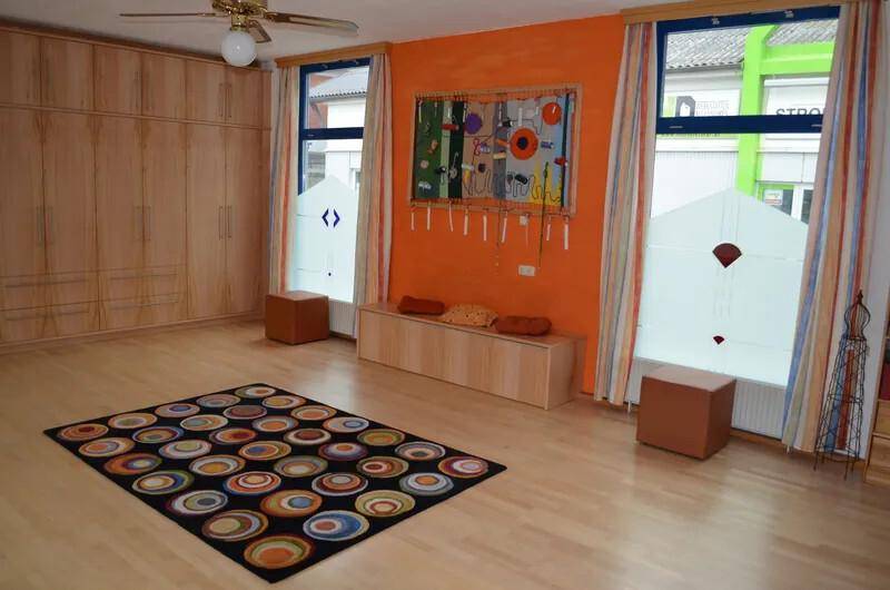 Helles Zimmer mit Einbauschränken, Parkettboden und farbenfrohem Teppich.