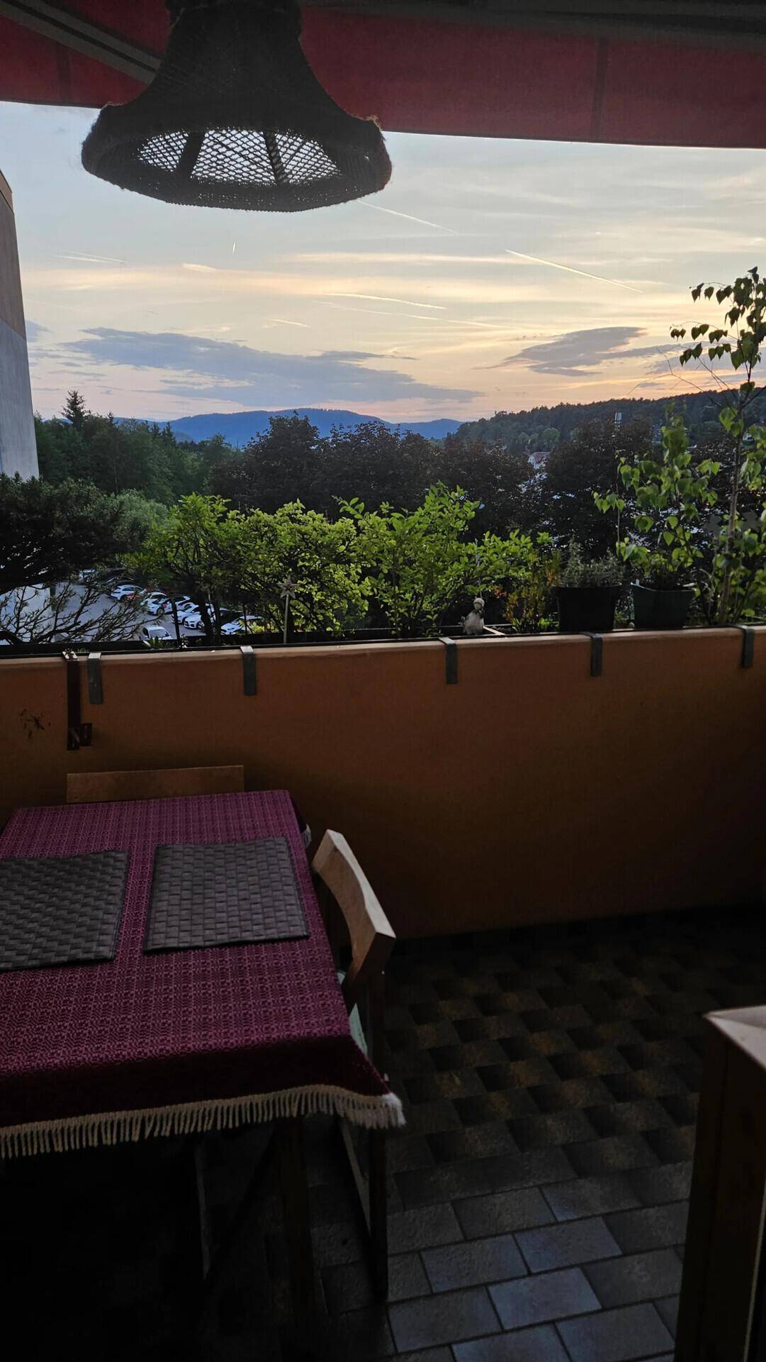 Balkon mit malerischem Ausblick auf die Berge und den Sonnenuntergang am Horizont.