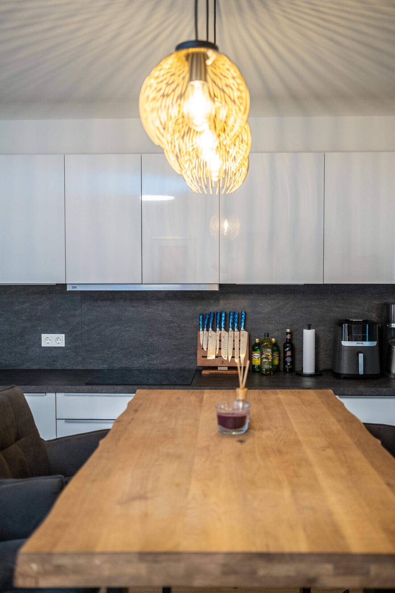 Detailansicht des Bartresens mit Holztischplatte und moderner Hängeleuchte über der Küche.