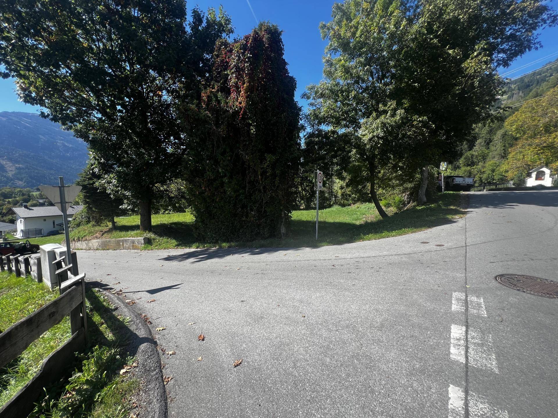 Zufahrtsstraße zum Grundstück mit umgebender Natur und einem Blick auf die entfernten Berge.