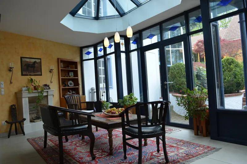 Heller Wintergarten mit Glasdach, Essbereich und Blick auf den Garten.