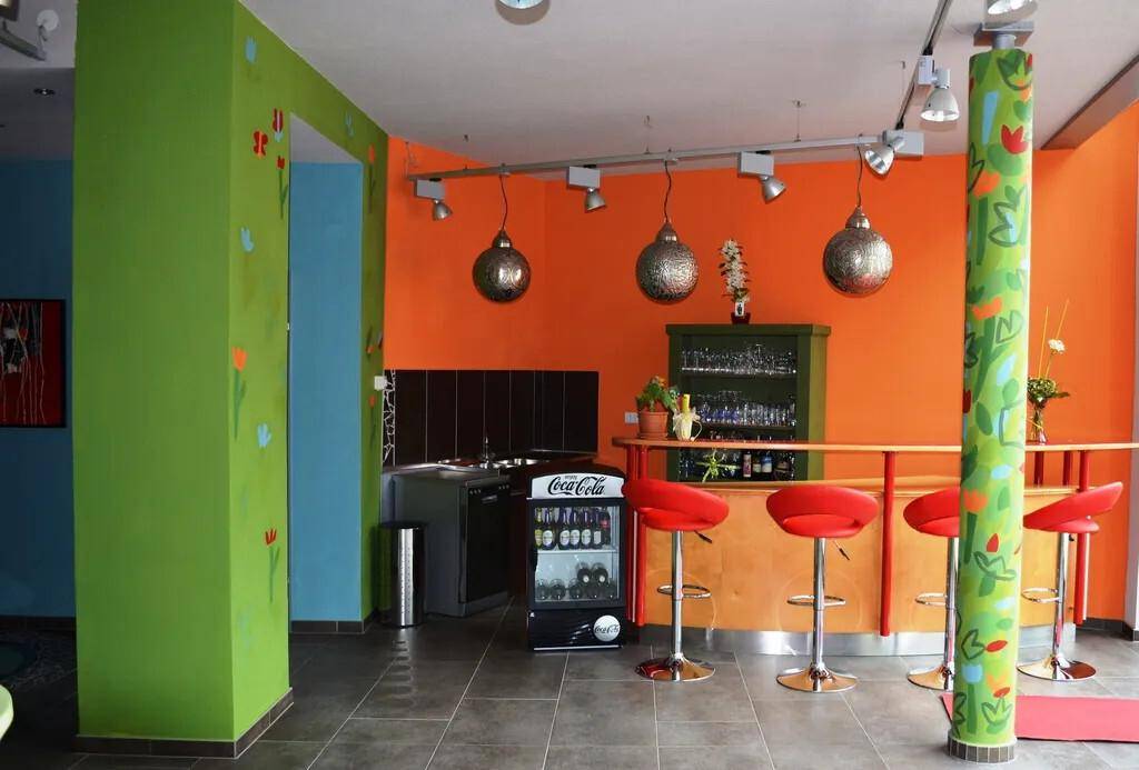 Farbenfrohe Küche mit Bar, Hockern und Kühlschrank.
