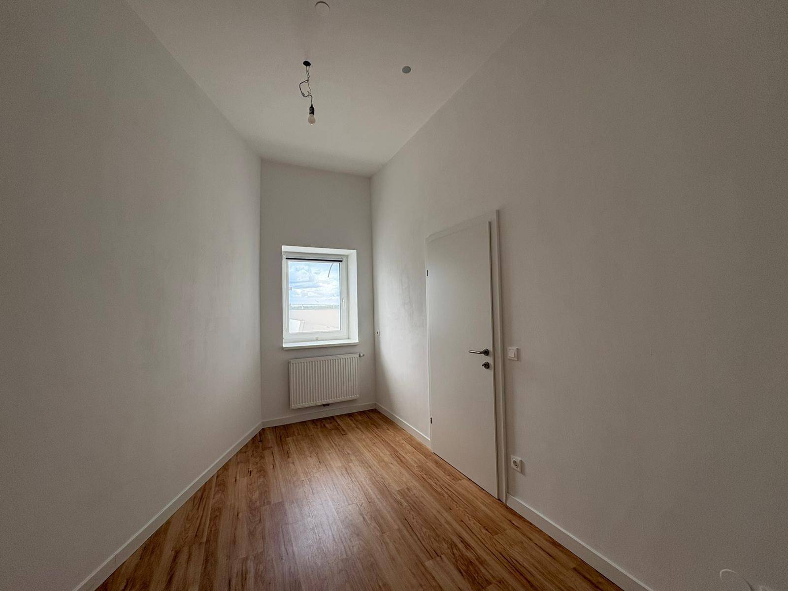 Kleines, helles Zimmer mit Fenster, Heizkörper und Laminatboden, ideal als Schlaf- oder Arbeitszimmer.