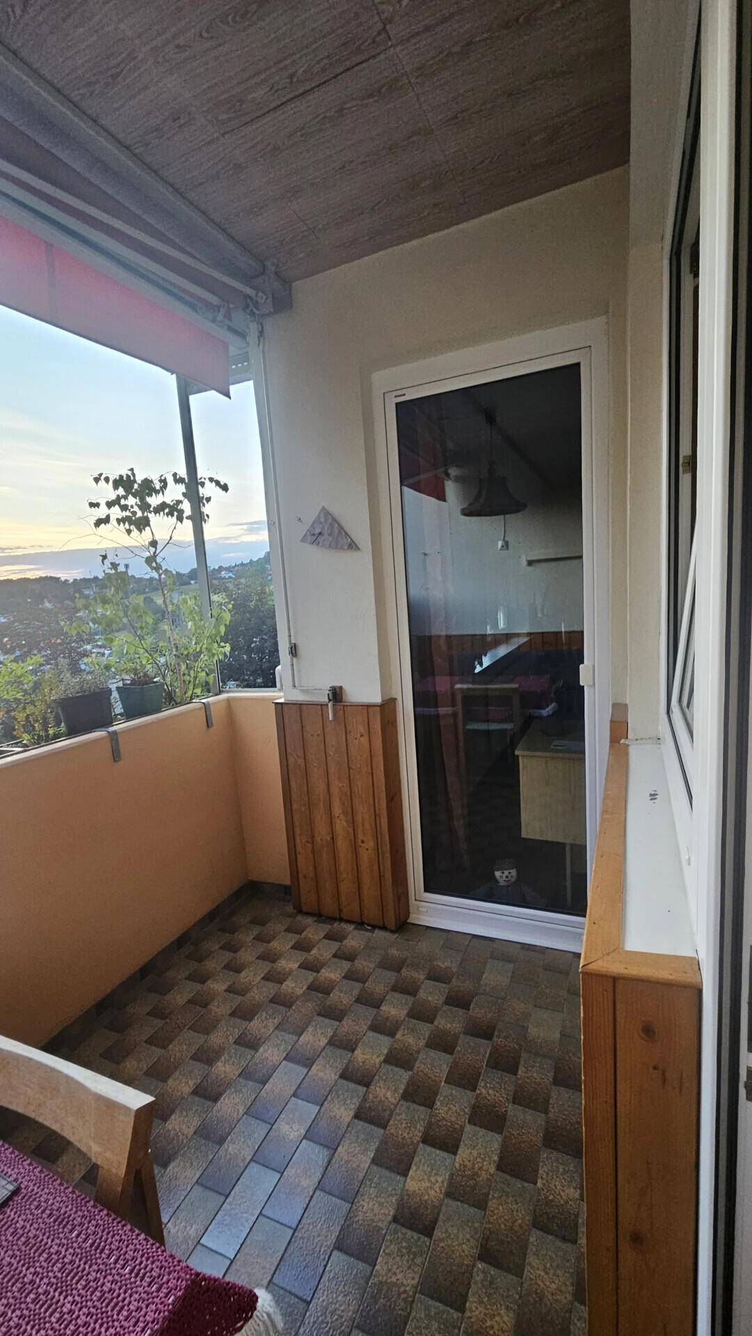 Balkon mit Fliesenboden und seitlichem Ausblick auf die umliegende Landschaft.