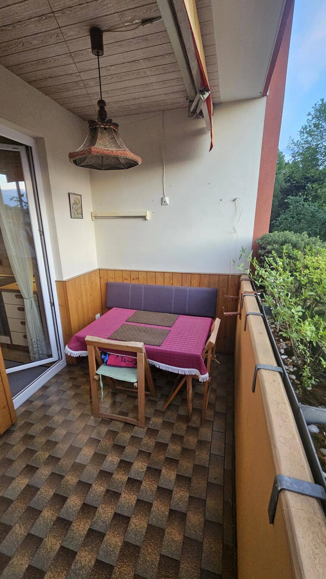 Gemütlicher Balkon mit Sitzgelegenheiten, Fliesenboden und Blick ins Grüne.